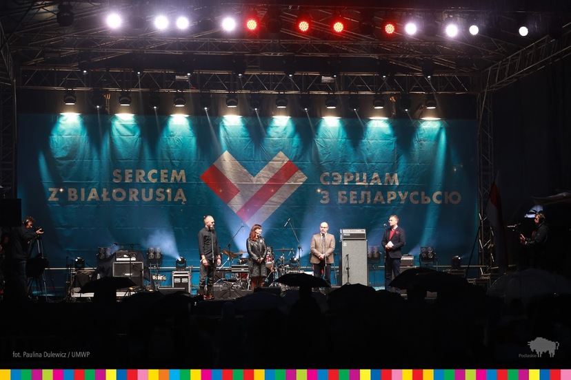 Na scenie marszałek Artur Kosicki w towarzystwie trzech osób. W tle napis w językach polskim i białoruskim: Sercem z Białorusią.