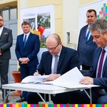 Marszałek Artur Kosicki i dyrektor Poliński podpisują umowę w obecności trzech mężczyzn.