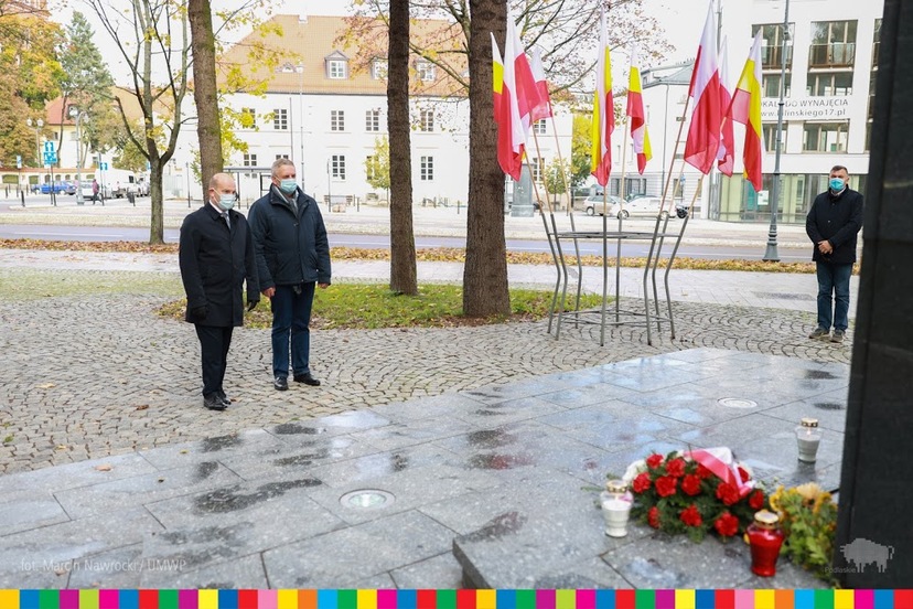 Dwóch mężczyzn stoi przed pomnikiem ks. Jerzego Popiełuszki.