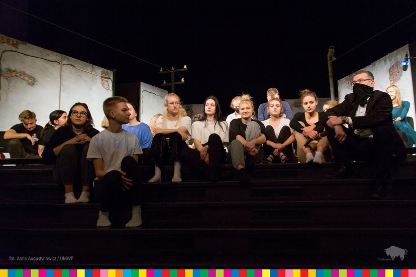 Grupa młodzieży siedzi na schodach sceny Teatru Dramatycznego
