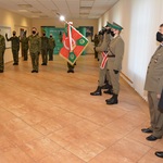 Kilkunastu żołnierzy stoi obok pocztu sztandarowego.