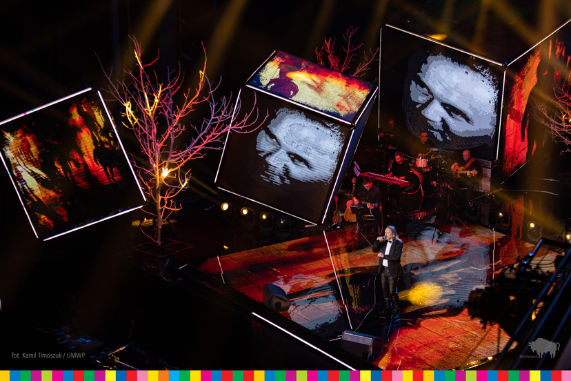 Marek Piekarczyk śpiewający na scenie i wyświetlane na telebimach zdjęcia Jana Pawła II