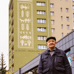 tsraszy mężczyzna stojący na chodniku przed muralem na bloku przy ul. M. Skłodowskiej-Curie w Białymstoku