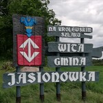 Tablice z herbem Jasionówki i napisem Na królewskim szlaku, wita Gmina Jasionówka