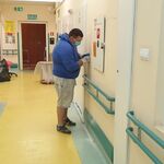 Mężczyzna malujący ścianę na szpitalnym korytarzu