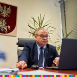 Wicemarszałek Województwa Podlaskiego Marek Olbryś siedzący przy laptopie.
