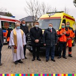 Na zdjęciu przed dwoma ambulansami stoi dziewięciu meżczyzn