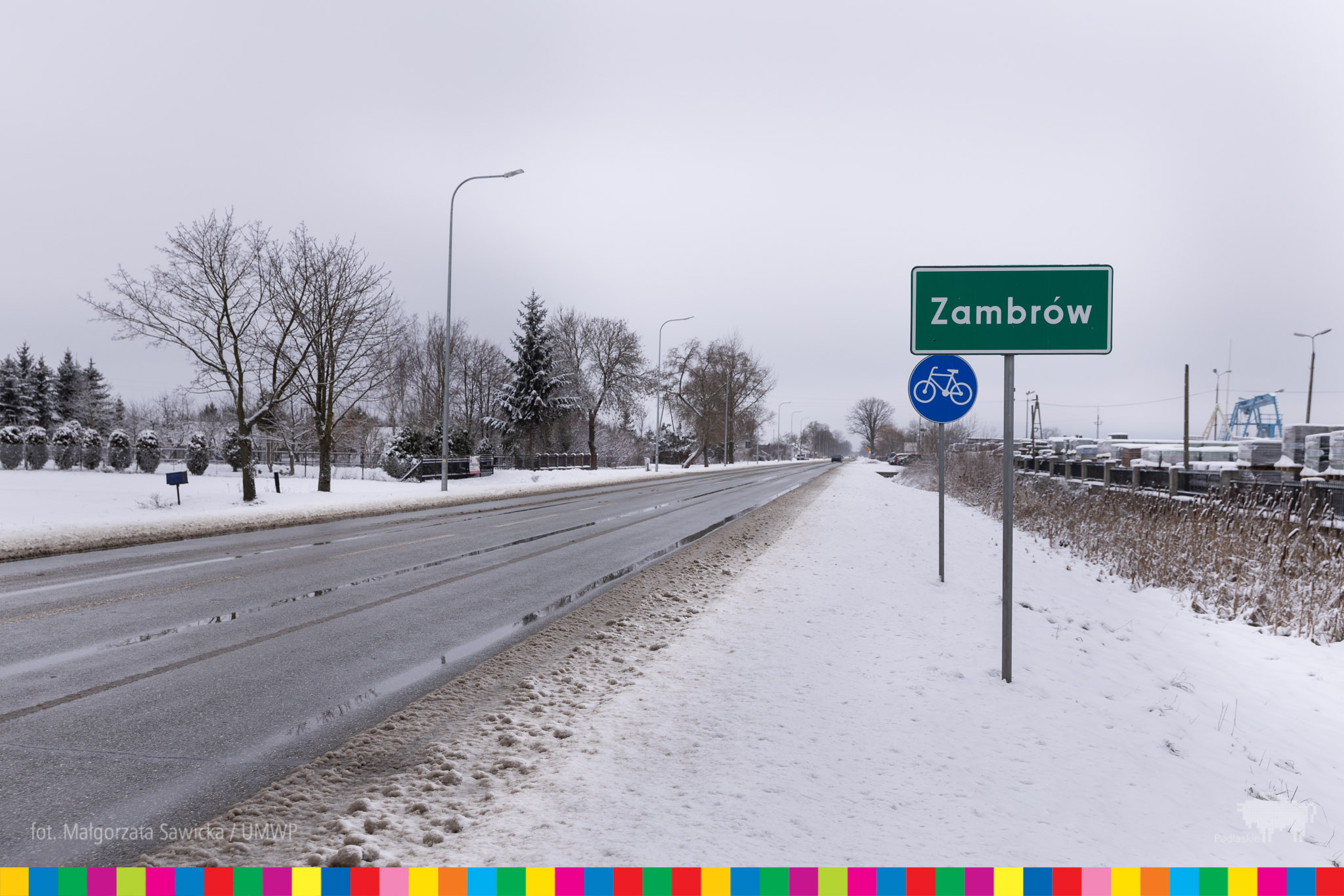 Znak drogowy z napisem Zambrów stojący na ośnieżonym poboczu przy drodze
