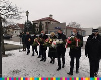 Grupa osób stoi z wiązankami kwiatów. W środku Wiesława Burnos, Członek Zarządu Województwa Podlaskiego.