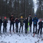 Grupa narciarzy stoi w zimowej leśnej scenerii