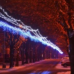 Fragment ulicy z iluminacjami w kształcie łańcuchów  wiszącymi pomiędzy latarniami.