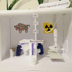 Praca przedstawia makietę wnętrza gabinetu gabinetu medycznego ze sprzętem do RTG, USG, EKG i robienia mammografii