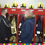 Wicemarszałek Marek Olbryś rozmawia ze strażakiem prezentującym nowe mundury strażackie.