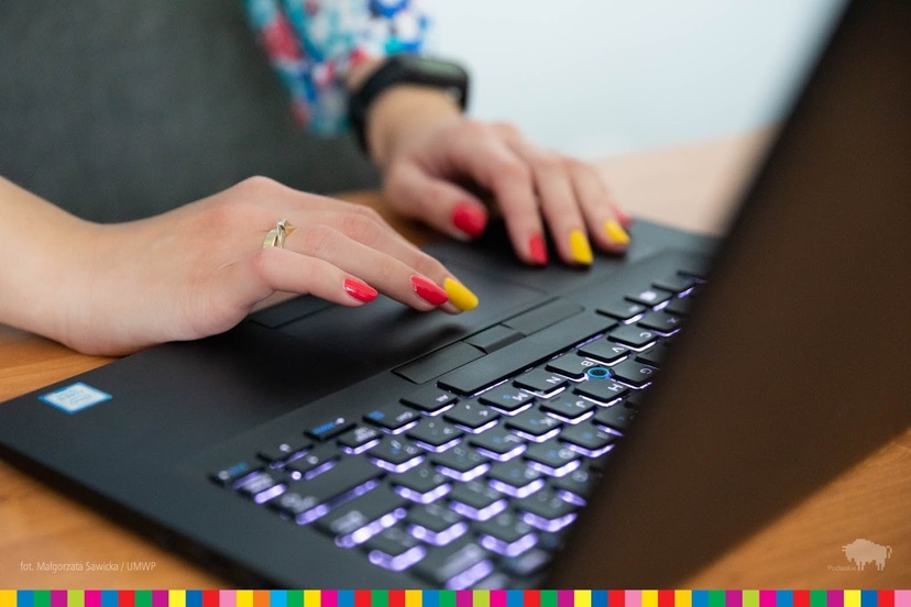 Kobiece dłonie przy klawiaturze laptopa.