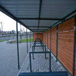 Stanowiska dla rowerów pod zadaszeniem przy ścianie dworca.