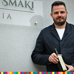 Łukasz Wasiluk, właściciel olejarni, stoi przed siedzibą firmy z butelką oleju w rękach
