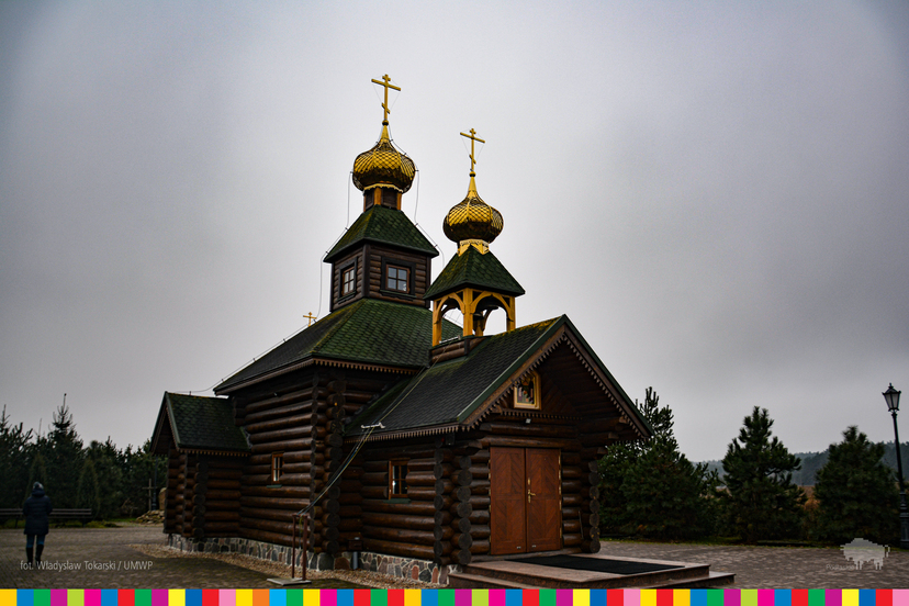 Drewniana cerkiew z dwiema wieżami uwieńczonymi złotymi kopułami z krzyżem prawosławnym.