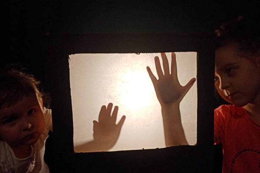 Dwie dziecięce dłonie na podświetlonej kartce.