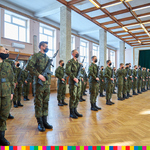 Na zdjęciu widoczni żołnierze trzymający broń, którzy stoją na baczność w dużej sali