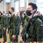 Żołnierze stojący na baczność z zakrytymi twarzami oraz trzymający broń w ręku