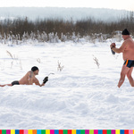 Po lewej mężczyzna leżący na śniegu, po prawej mężczyzna stoi. W tle łąka