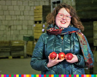Kobieta trzyma w dłoniach kilka czerwonych jabłek