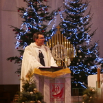 Na zdjęciu widoczny ksiądz w ornacie stojący za amboną. Za nim widoczne tabernakulum oraz przystrojone łańcuchami i lampkami choinki