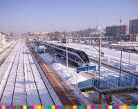 Pociąg stojący na peronie dworca PKP. Obok pociągu widać tory kolejowe