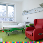 Sala szpitalna z łóżkiem i fotelem.