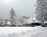 Zaśnieżony teren. W tle chata z pokrywą śnieżną.