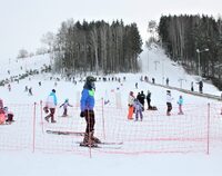Kilkadziesiąt osób na ośnieżonej górze, na pierwszym planie młody chłopak na nartach