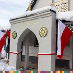 Fragment meczetu z dwiema flagami biało-czerwonymi i dwiema flagami Zjednoczonych Emiratów Arabskich.