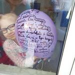 Dziewczynka pokazuje balon przez okno.