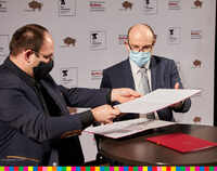 Marszałek Województwa Podlaskiego Artur Kosicki oraz Piotr Półtorak, dyrektor Teatru Dramatycznego w Białymstoku podają sobie teczkę z dokumentami do podpisu.