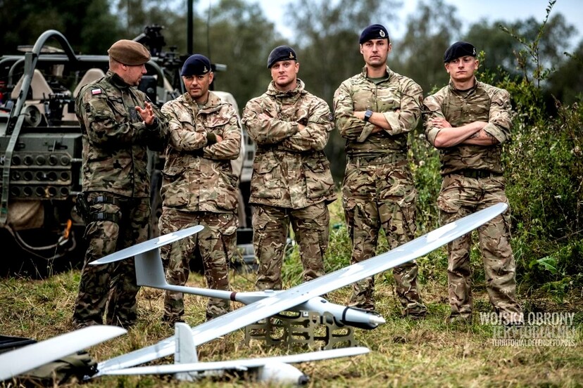 Grupa żołnierzy stoi obok samolotu bezzałogowego.