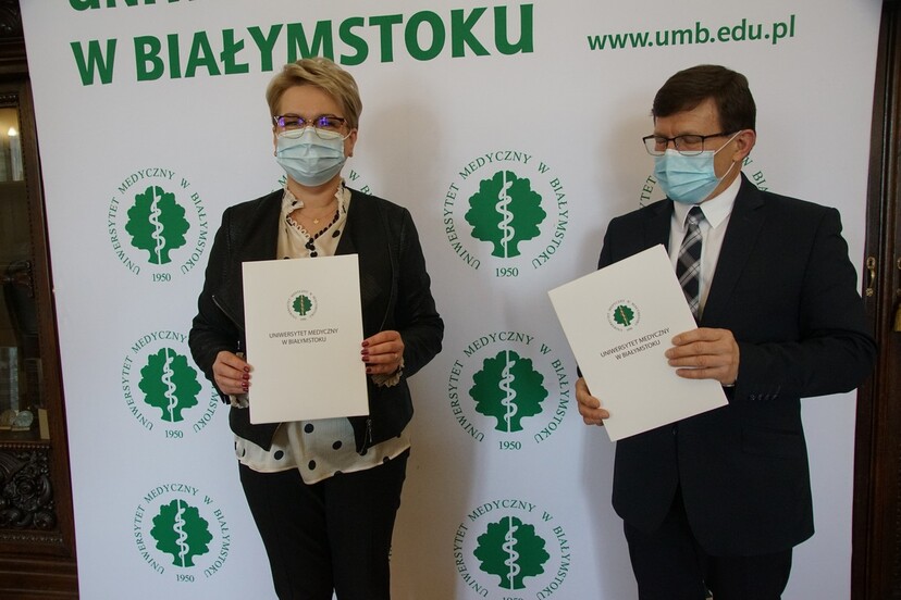 Profesor Janusz Dzięcioł i dyrektor Ewa Zgiet stoją trzymając w rękach egzemplarze umowy.