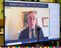Ekran monitora, na którym widać mówiącego mężczyznę w okularach