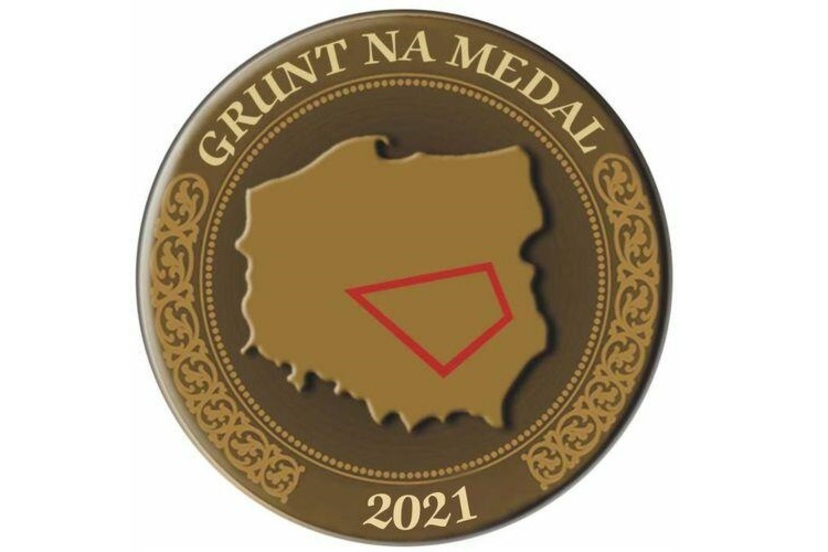 Grafika ukazująca brązowy medal. Wewnątrz koło jest mapa Polski z umieszczonym czworobokiem