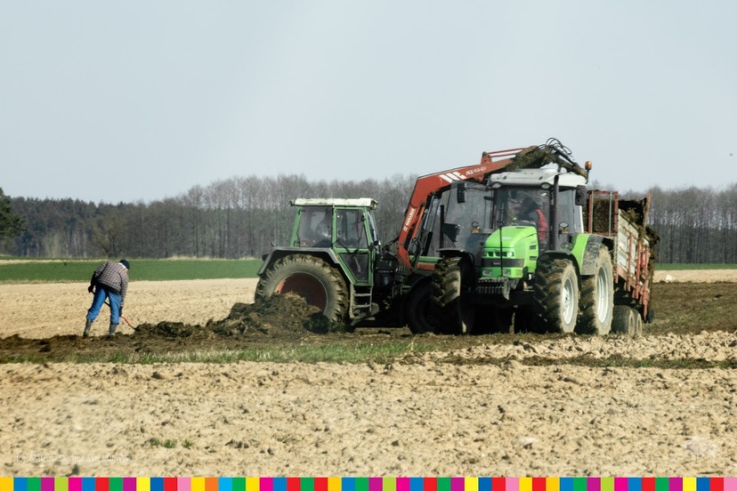Widoczne maszyny rolnicze oraz rolnik pracujący w polu