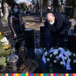 Marszałek Artur Kosicki kładzie kwiaty na nagrobku. Na zdjęciu widoczne po jego prawej stronie dwie osoby.