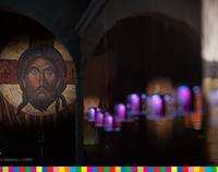 Widoczna ikona, na której widoczna jest twarz Jezusa Chrystusa. Po prawej wiszące niebieskie świeczki