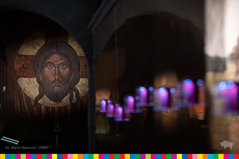 Widoczna ikona, na której widoczna jest twarz Jezusa Chrystusa. Po prawej wiszące niebieskie świeczki