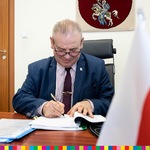 Wicemarszałek Olbryś podpisuje dokumenty siedząc za biurkiem