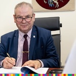 Marszałek Marek Olbryś siedzi za biurkiem podpisując dokumenty