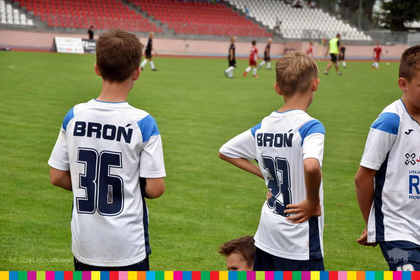 Troje młodych piłkarzy na murawie boiska.