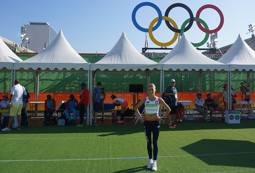 Iwona Bernardelli w stroju uczestnika Igrzysk Olimpijskich w Rio. W tle logo MKOL