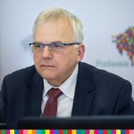 Bogusław Dębski, przewodniczący sejmiku województwa, siedzący podczas obrad sejmiku na tle ścianki promocyjnej województwa