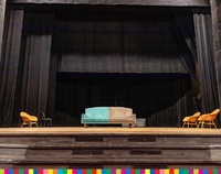 Kanapa, cztery krzesła i wieszak stoją na scenie