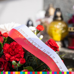 Biało-czerwona szarfa przy kwiatowym wieńcu z napisem Artur Kosicki wraz.... W tele widoczne są znicze
