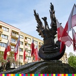 pomnik przedstawiający orła stojącego na tarczy amazonki. Obok powiewają biało-czerwone sztandary
